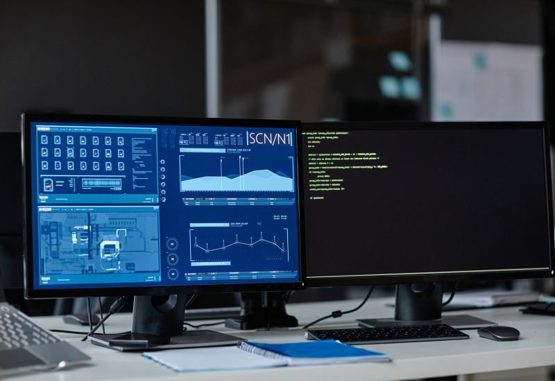 Front view background image of two computers with data charts on screen at workplace in security department copy space