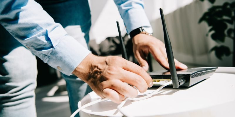 cropped view of businessman plugging router on white table