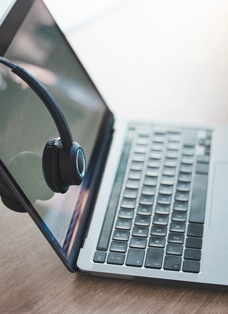 Laptop, headphones and call center telemarketing background on desk in office for contact us, video.