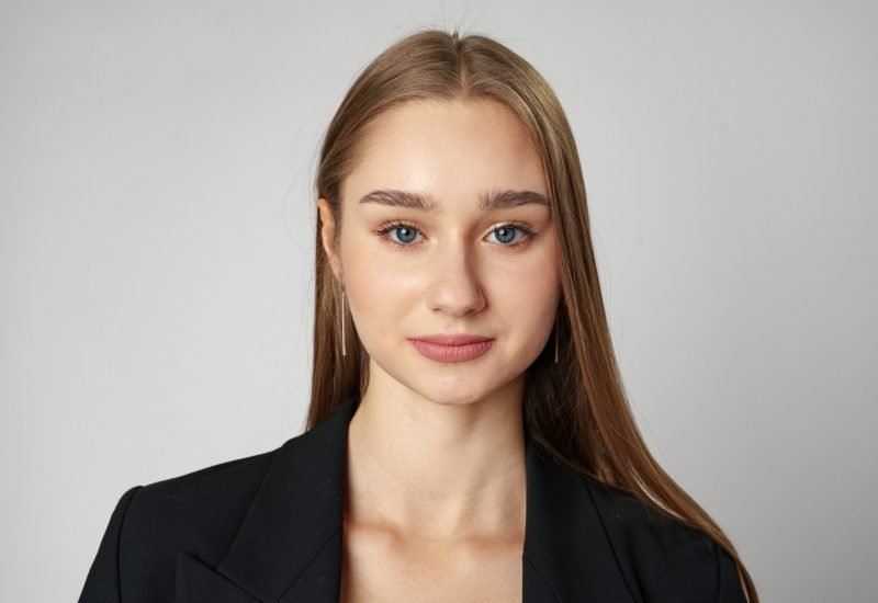 Young Woman in Black Jacket Posing to Camera against gray background close up